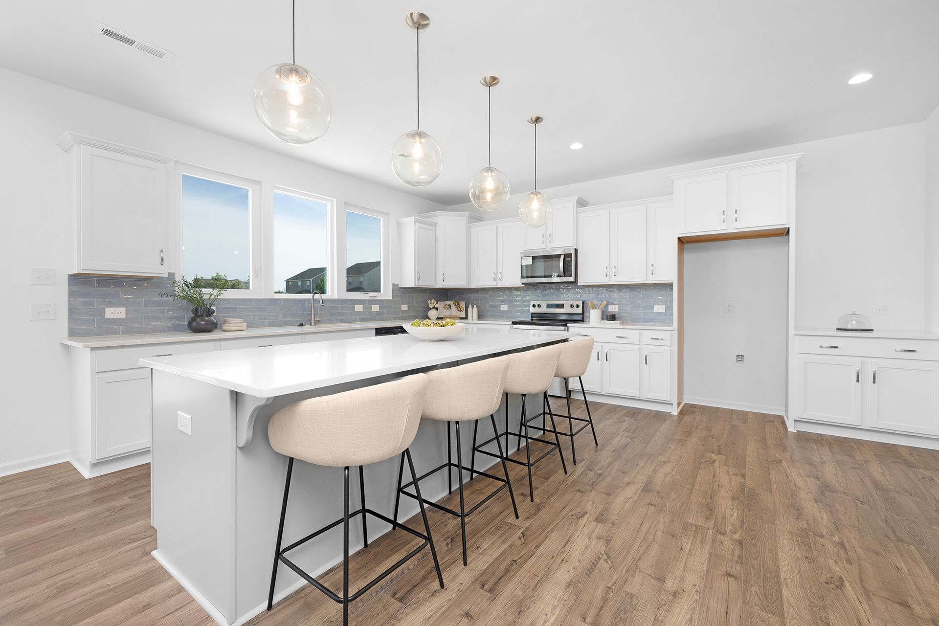 A kitchen with white cabinets , a large island , and wooden floors.