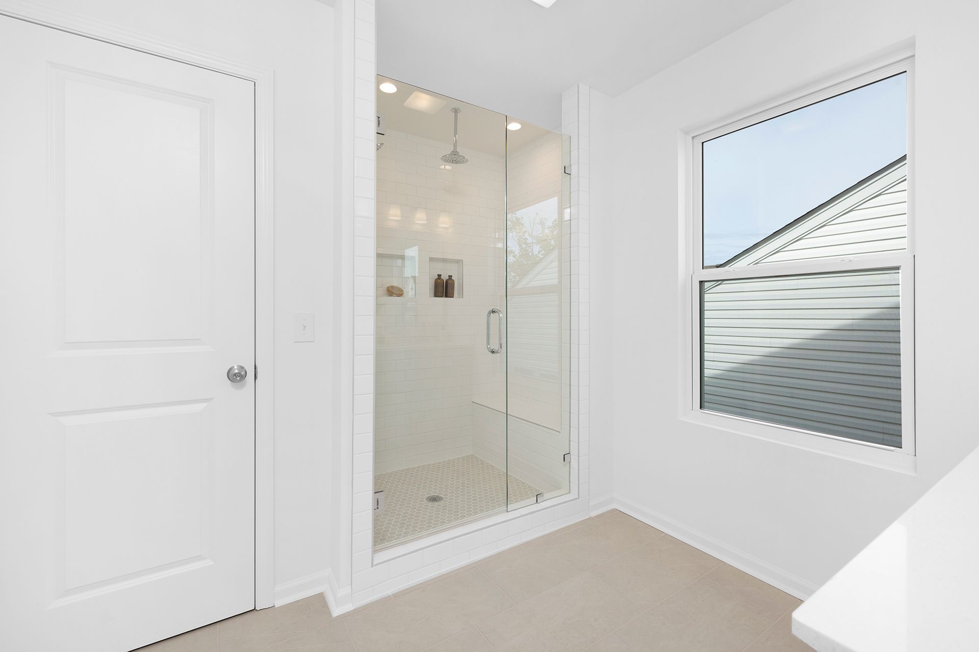 A bathroom with a walk in shower and a window.