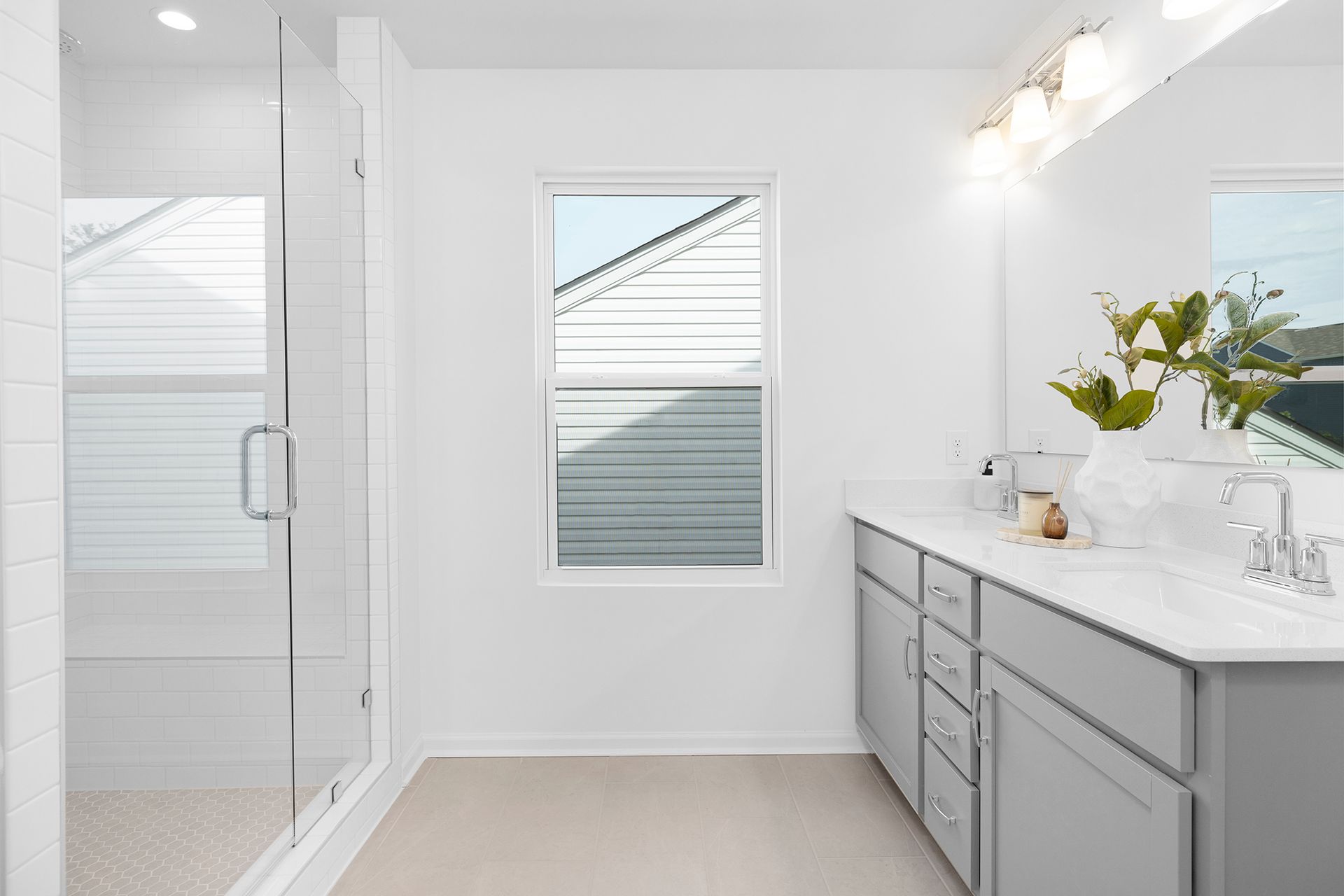 A bathroom with two sinks , a walk in shower and a window.