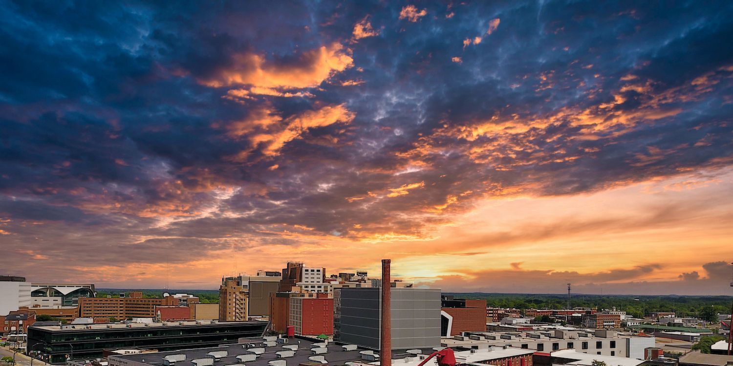 An aerial view of a city at sunset with a cloudy sky.