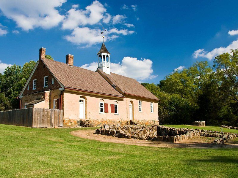 A large house with a clock tower in the middle of a grassy field.