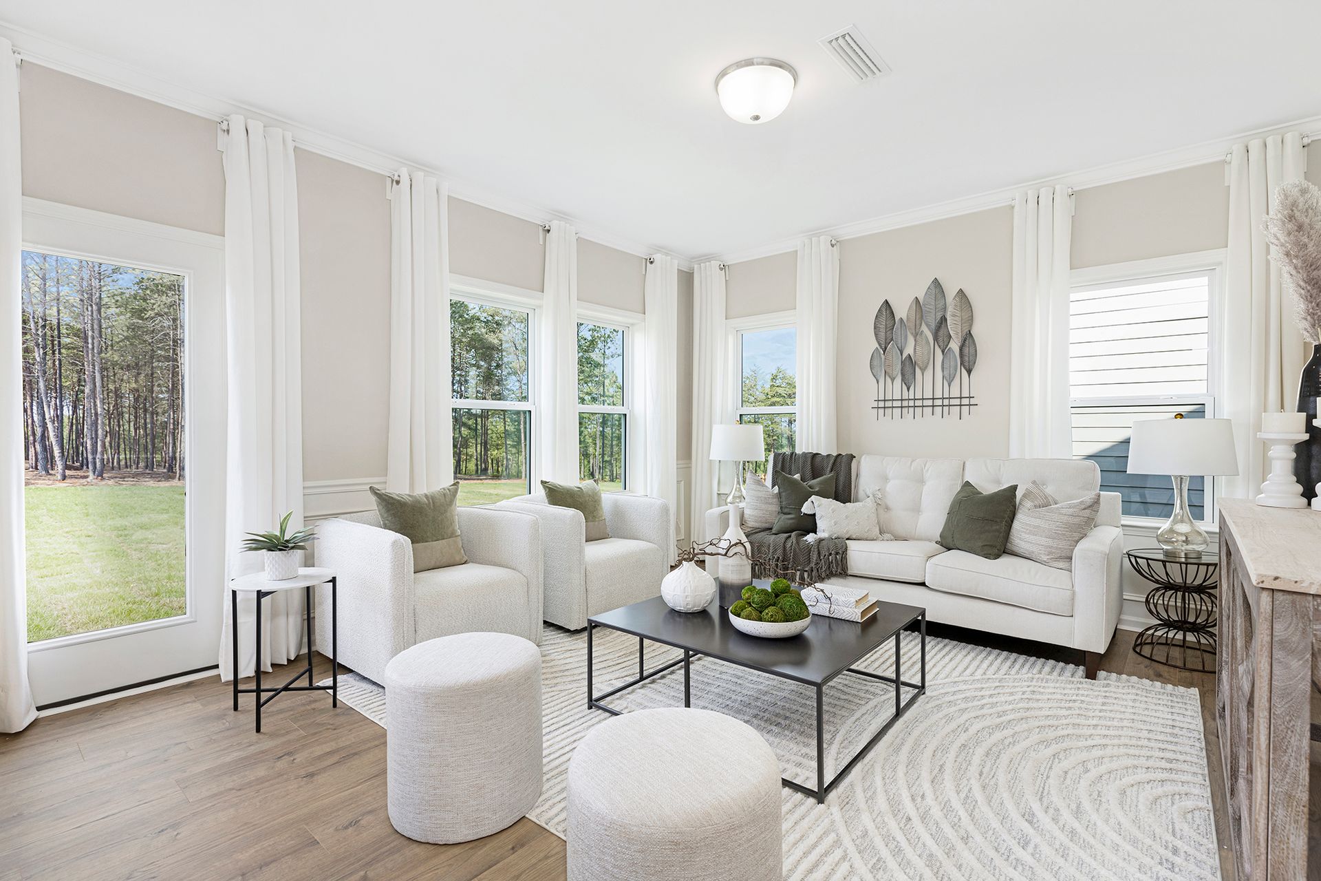 A living room with a couch , chairs , ottomans and a coffee table.