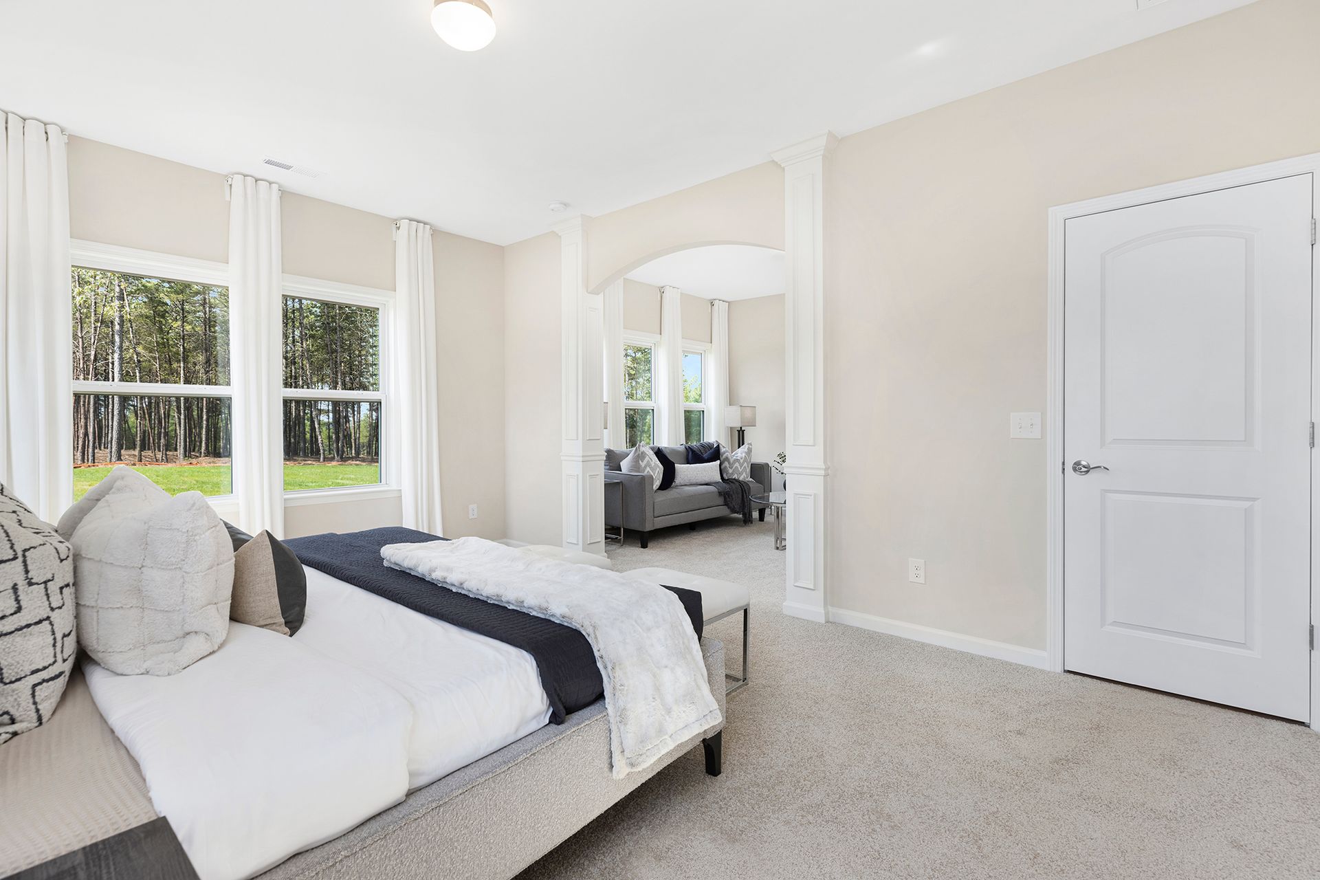 A bedroom in a model home with a large bed and a couch.