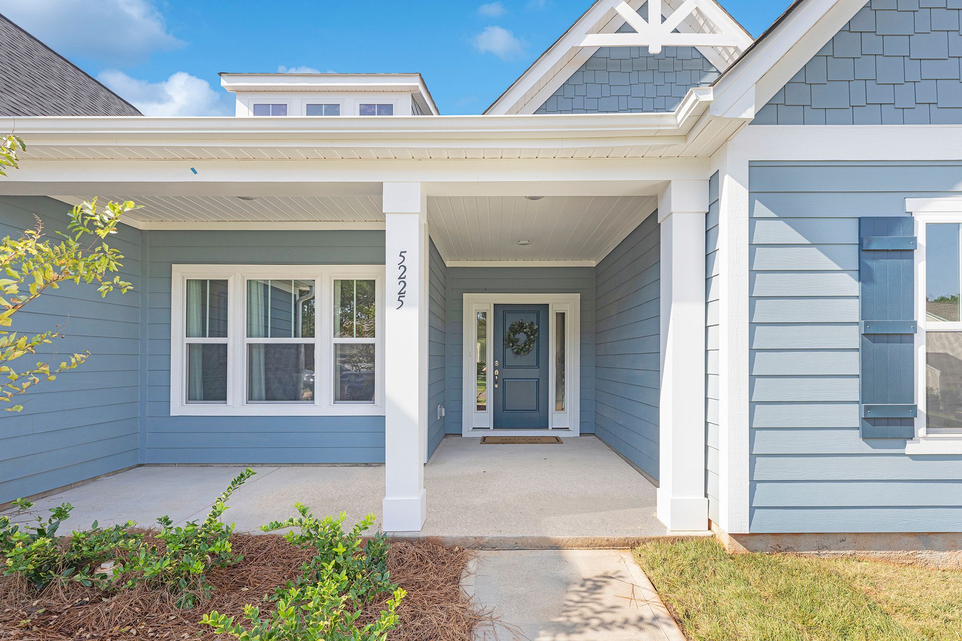 A blue and white house with a porch and a blue door