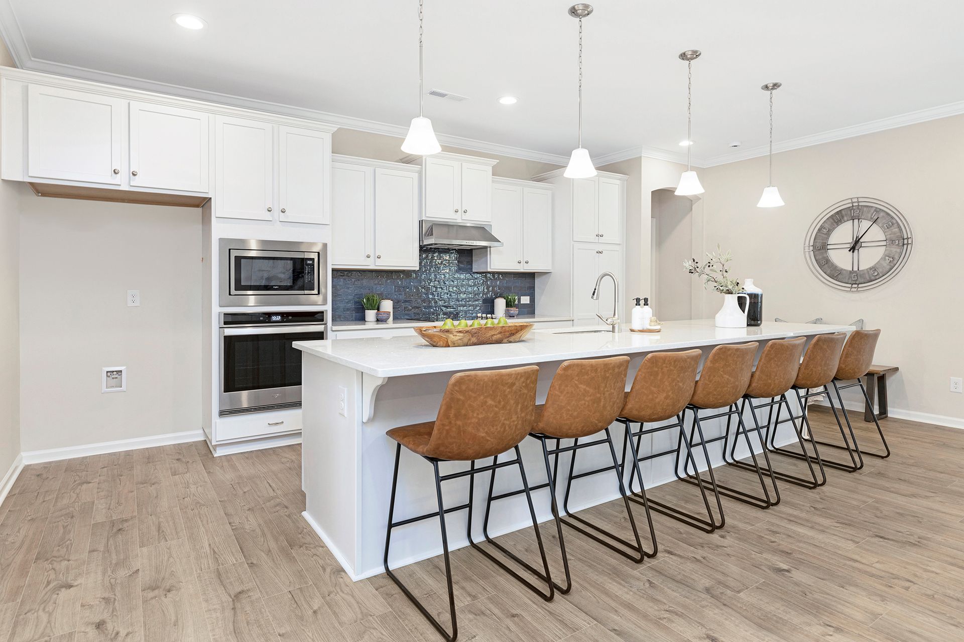 A kitchen with white cabinets , stainless steel appliances , and a large island.