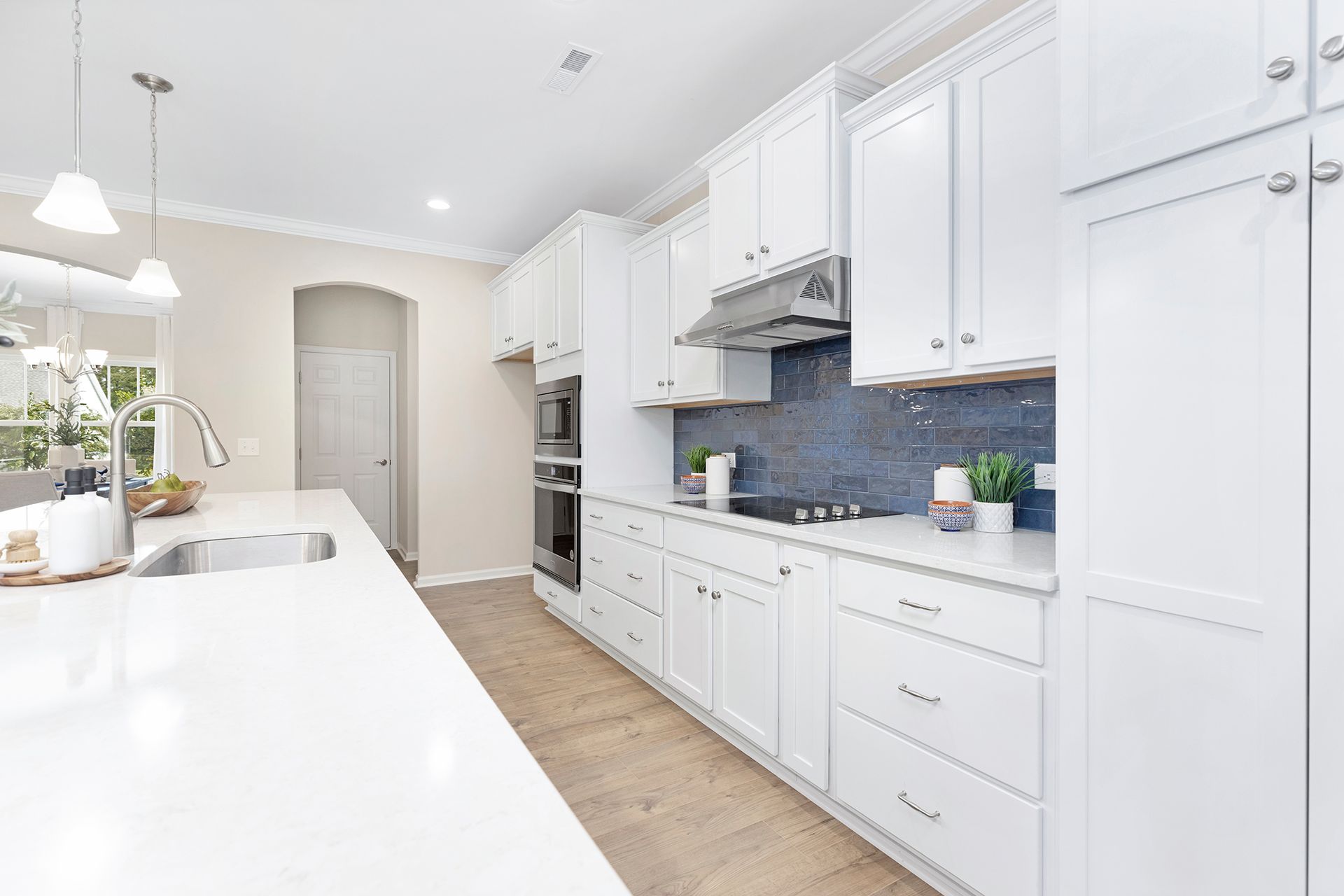 A kitchen with white cabinets , stainless steel appliances , and a large island.