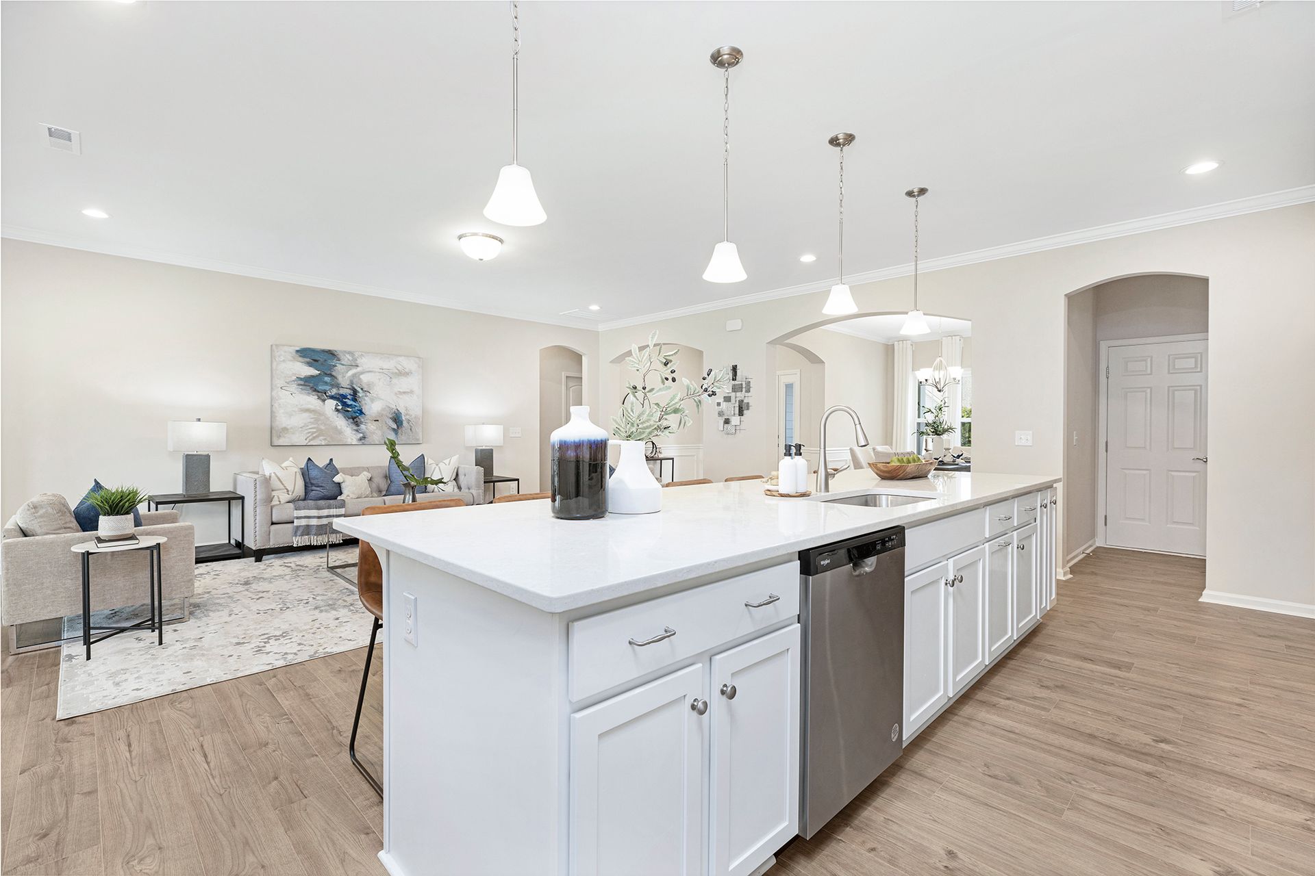 A kitchen with white cabinets and stainless steel appliances and a large island.