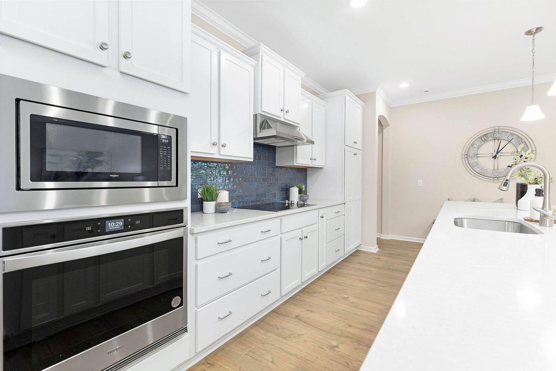 A kitchen with white cabinets , stainless steel appliances , a microwave and a sink.