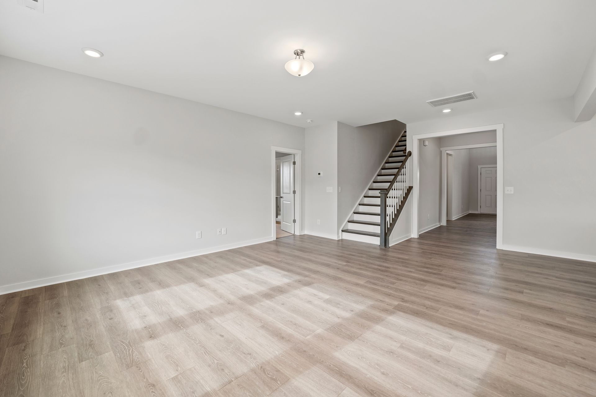 An empty living room with hardwood floors and stairs in a house.