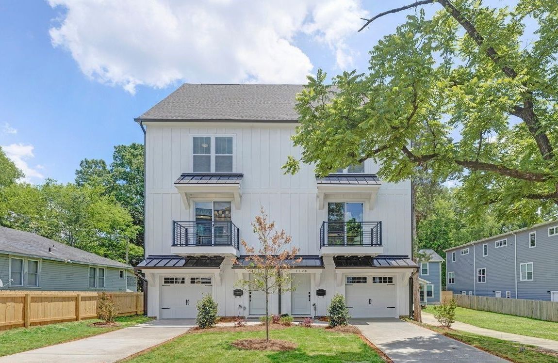 A white house with two garages and a fence in front of it.