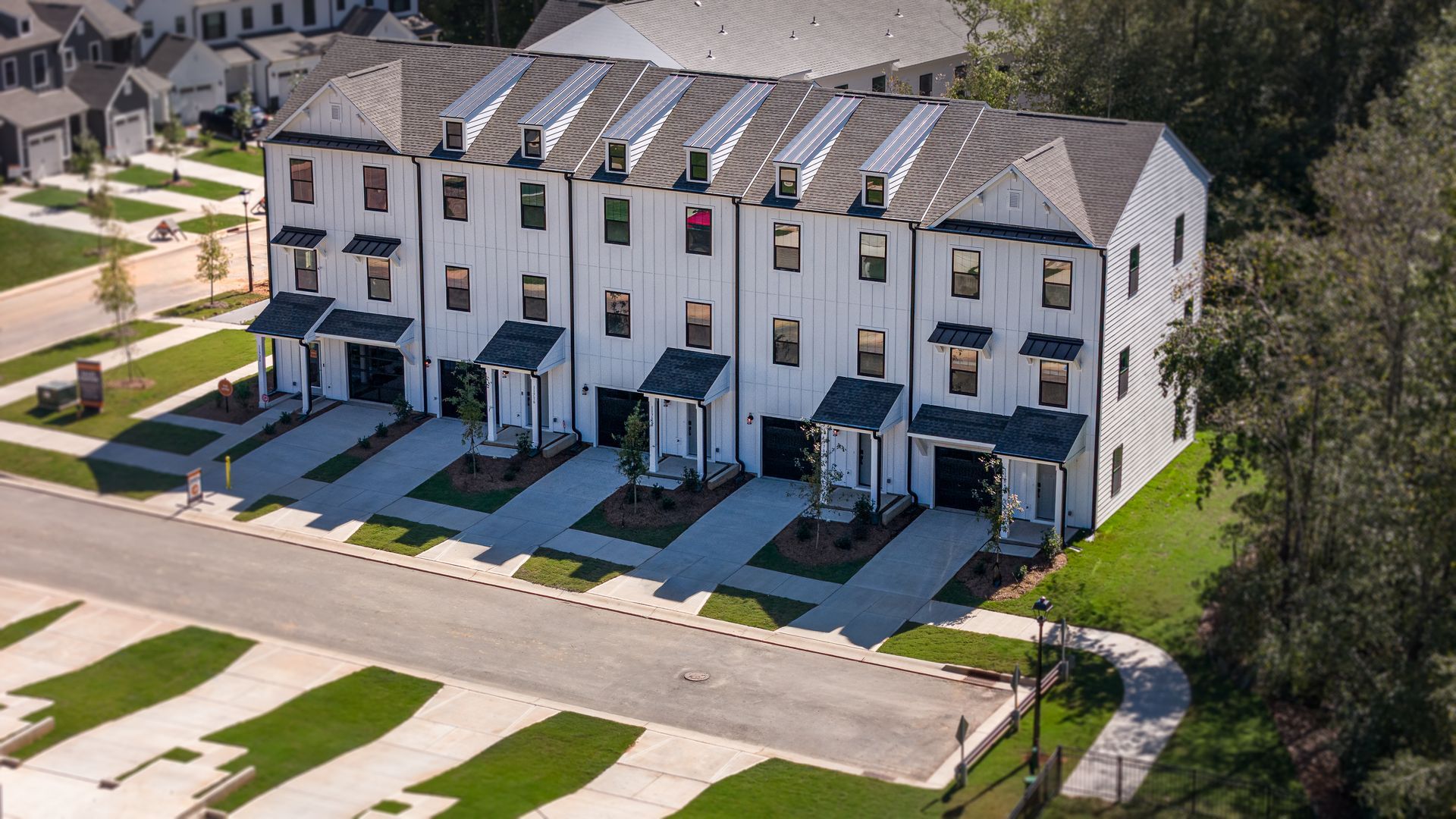 White townhouses with dark trim, garage, and glass front door.