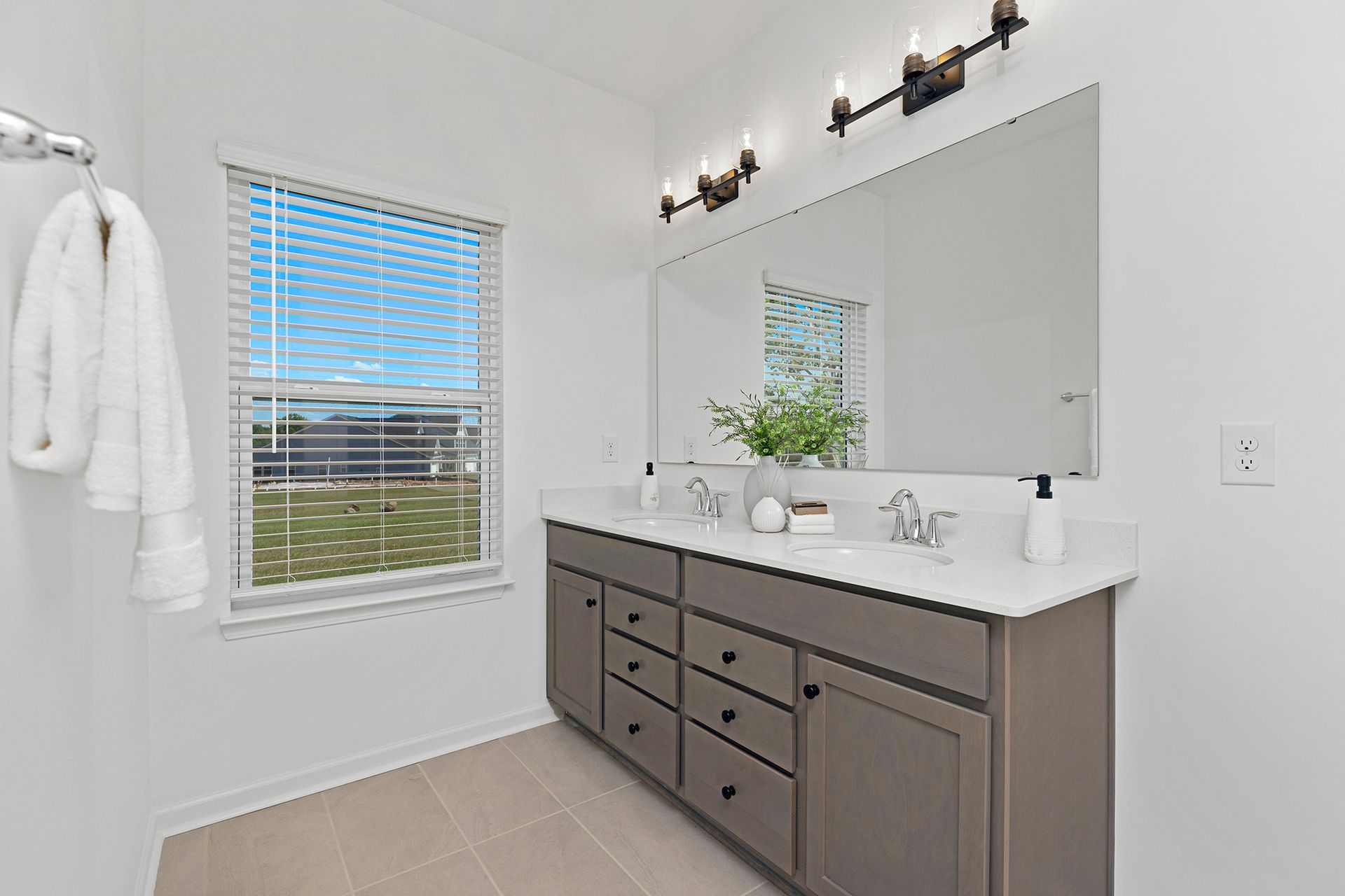 A bathroom with two sinks , a large mirror and a window.