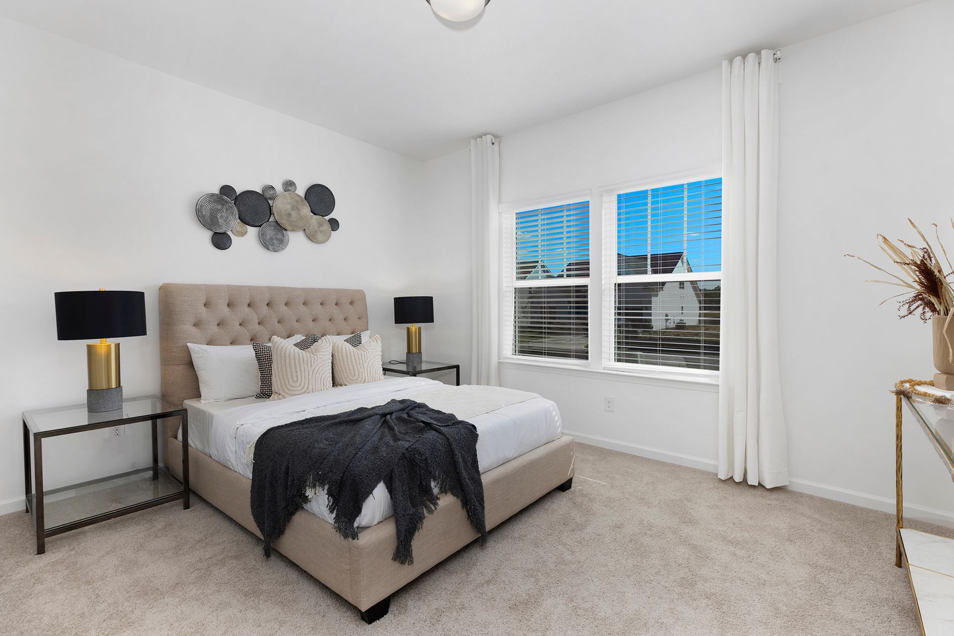 A bedroom with a bed , two lamps , and two windows.