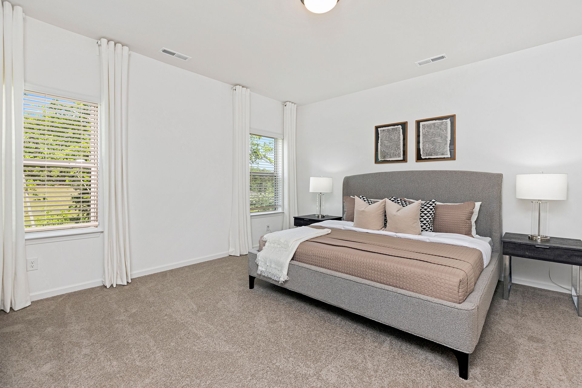 A bedroom with a large bed , lamps , and a window.