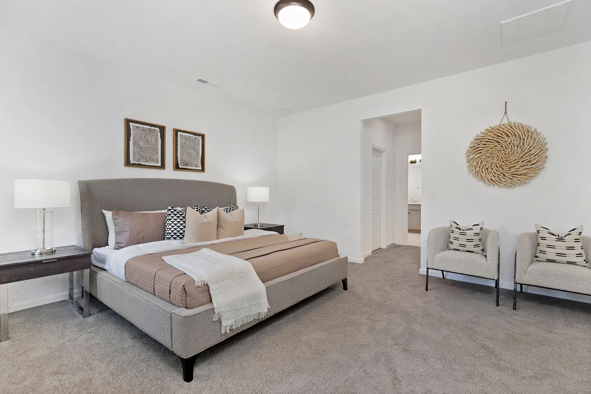 A bedroom with a king size bed , chairs , lamps and a ceiling fan.