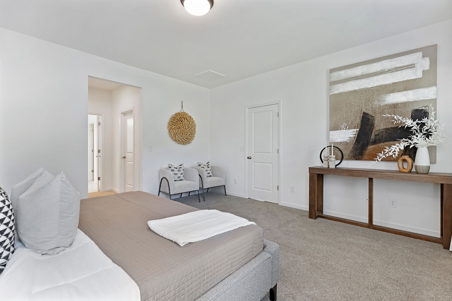 A bedroom with a bed , chairs , a table and a painting on the wall.