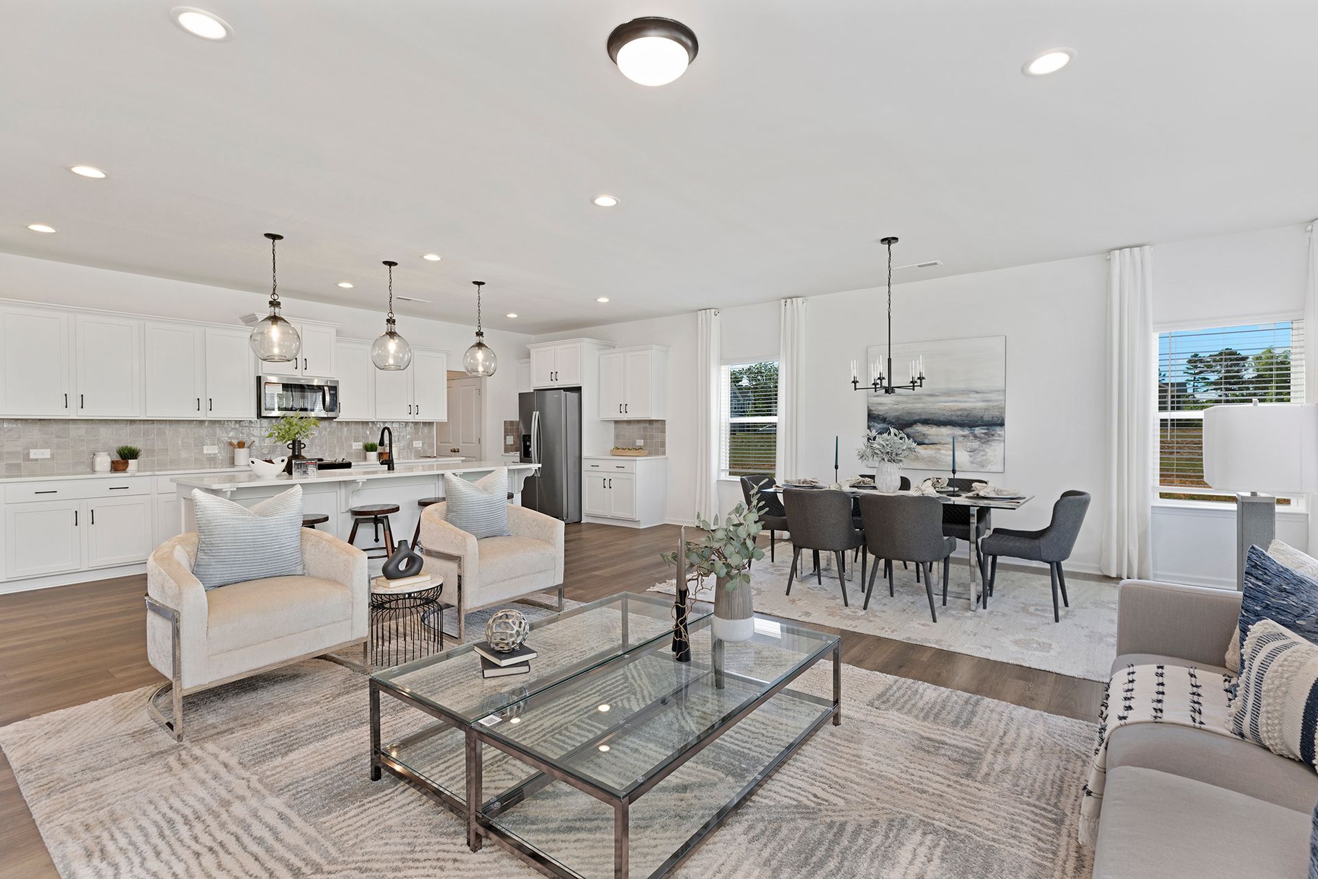 A living room with a glass coffee table , chairs , and a dining room.