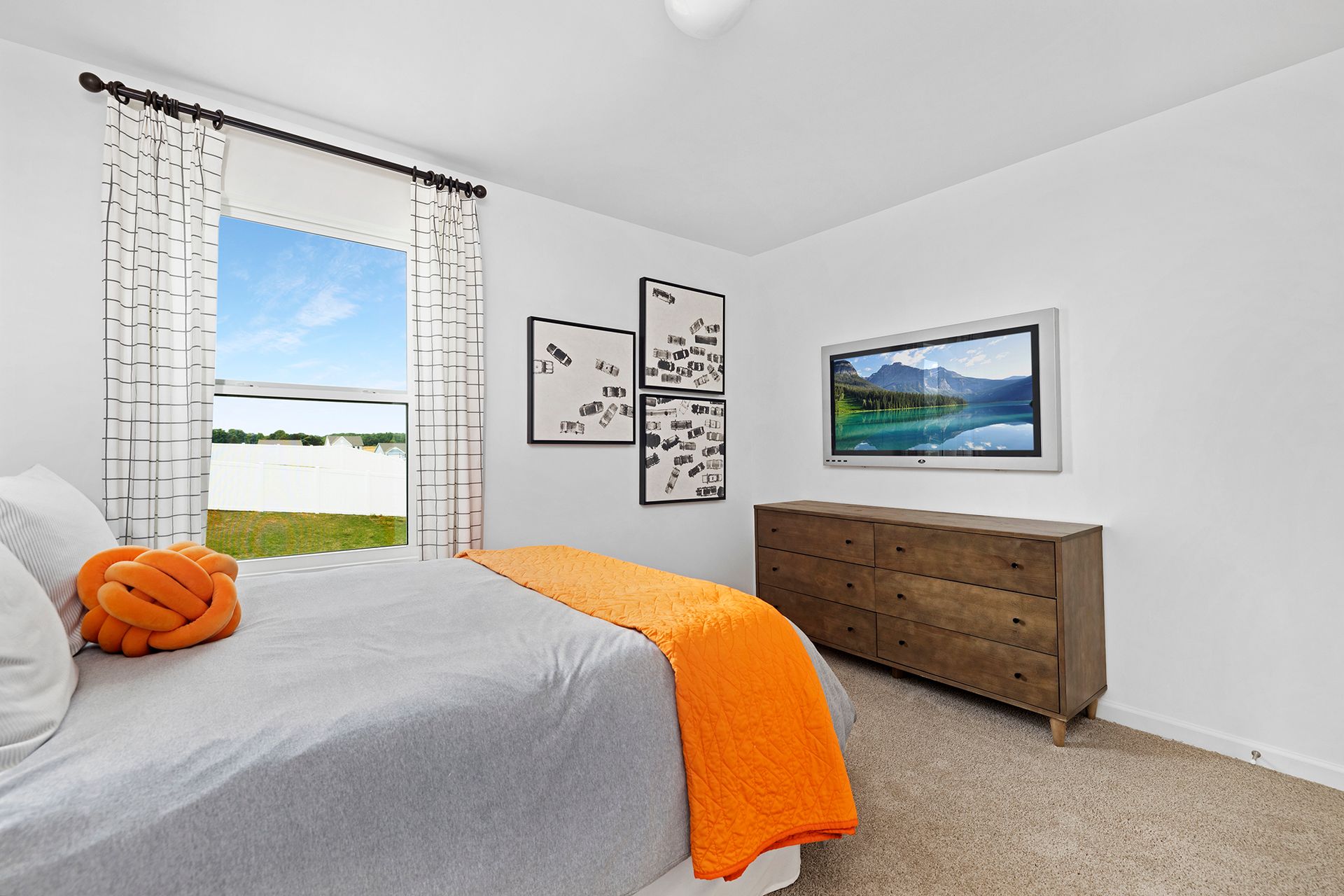 A bedroom with a bed , dresser , and television on the wall.