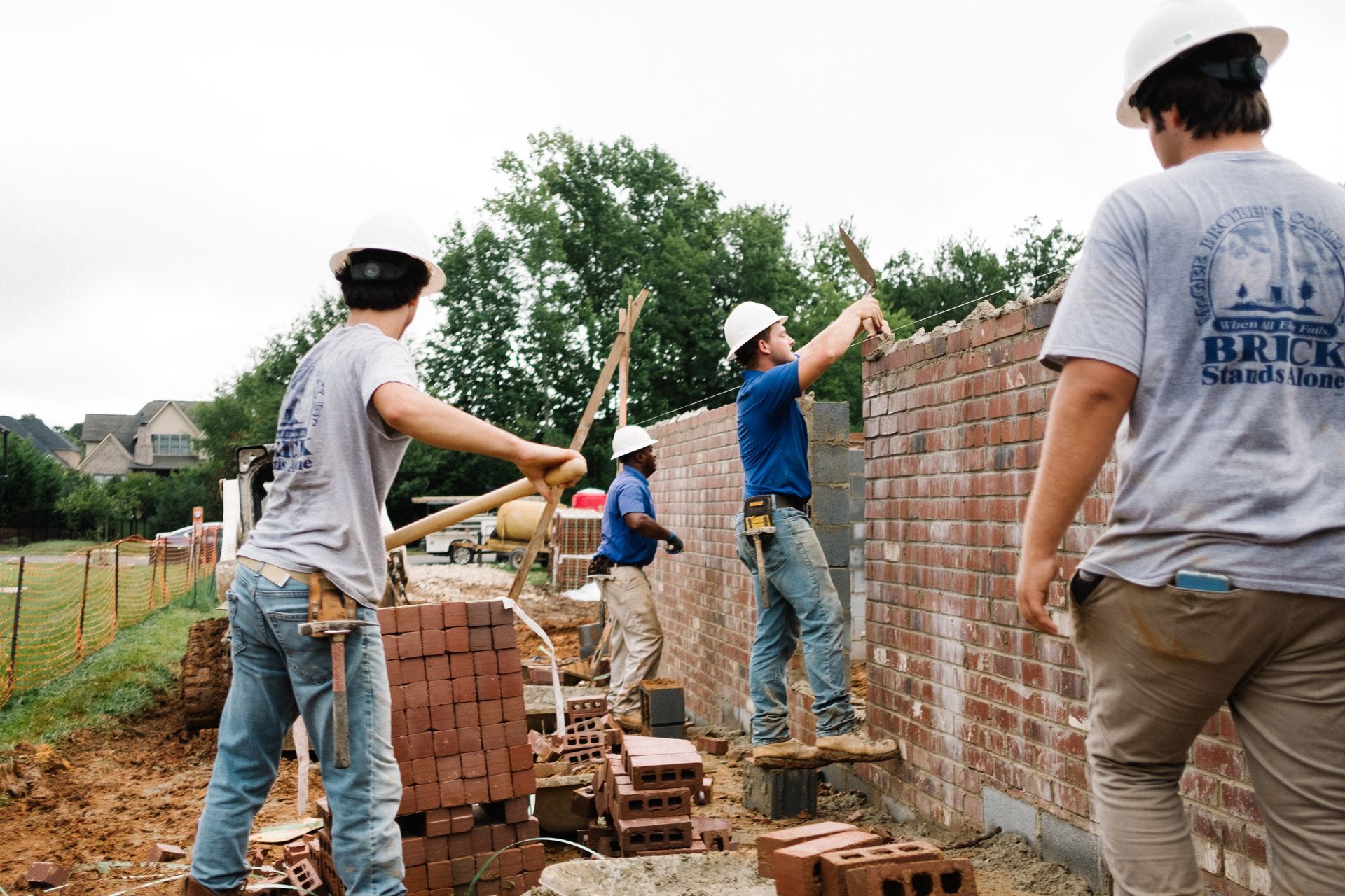 A group of construction workers are working on a brick wall.