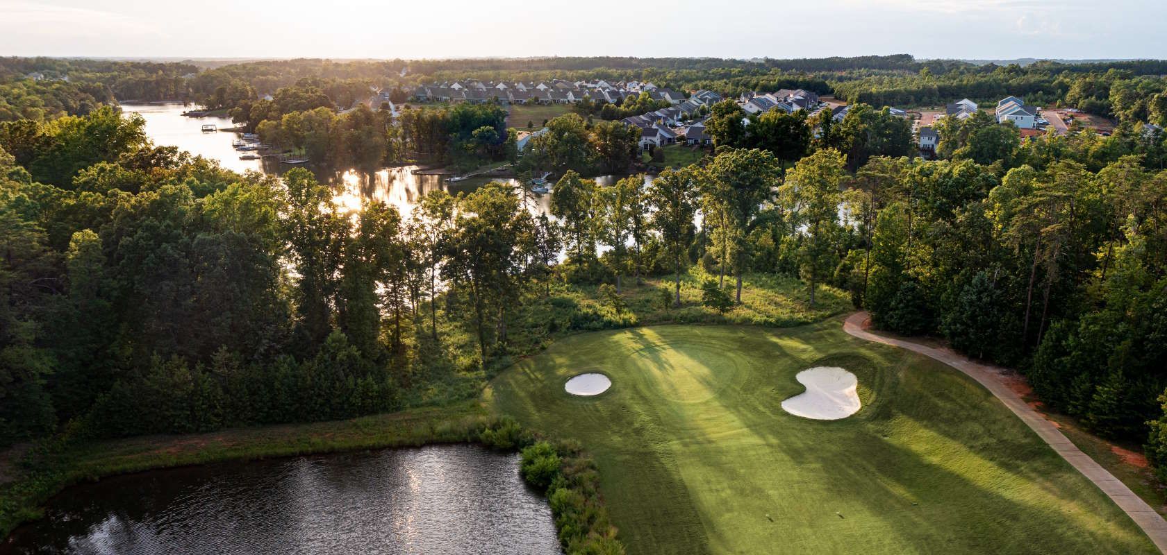 an aerial view of a golf course with a lake in the background