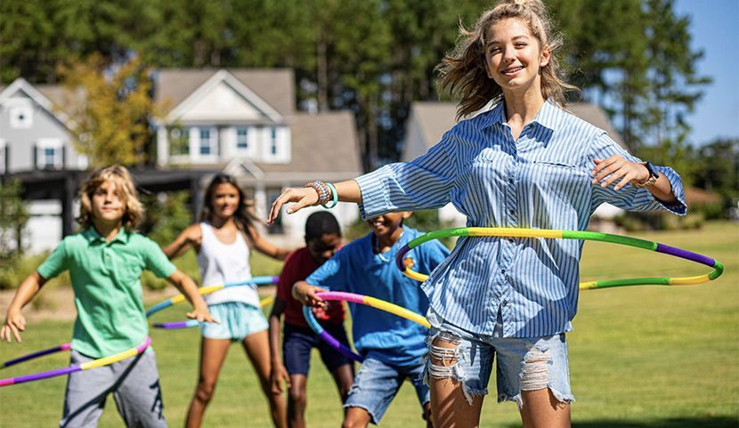 A group of children are playing with hula hoops in a field.