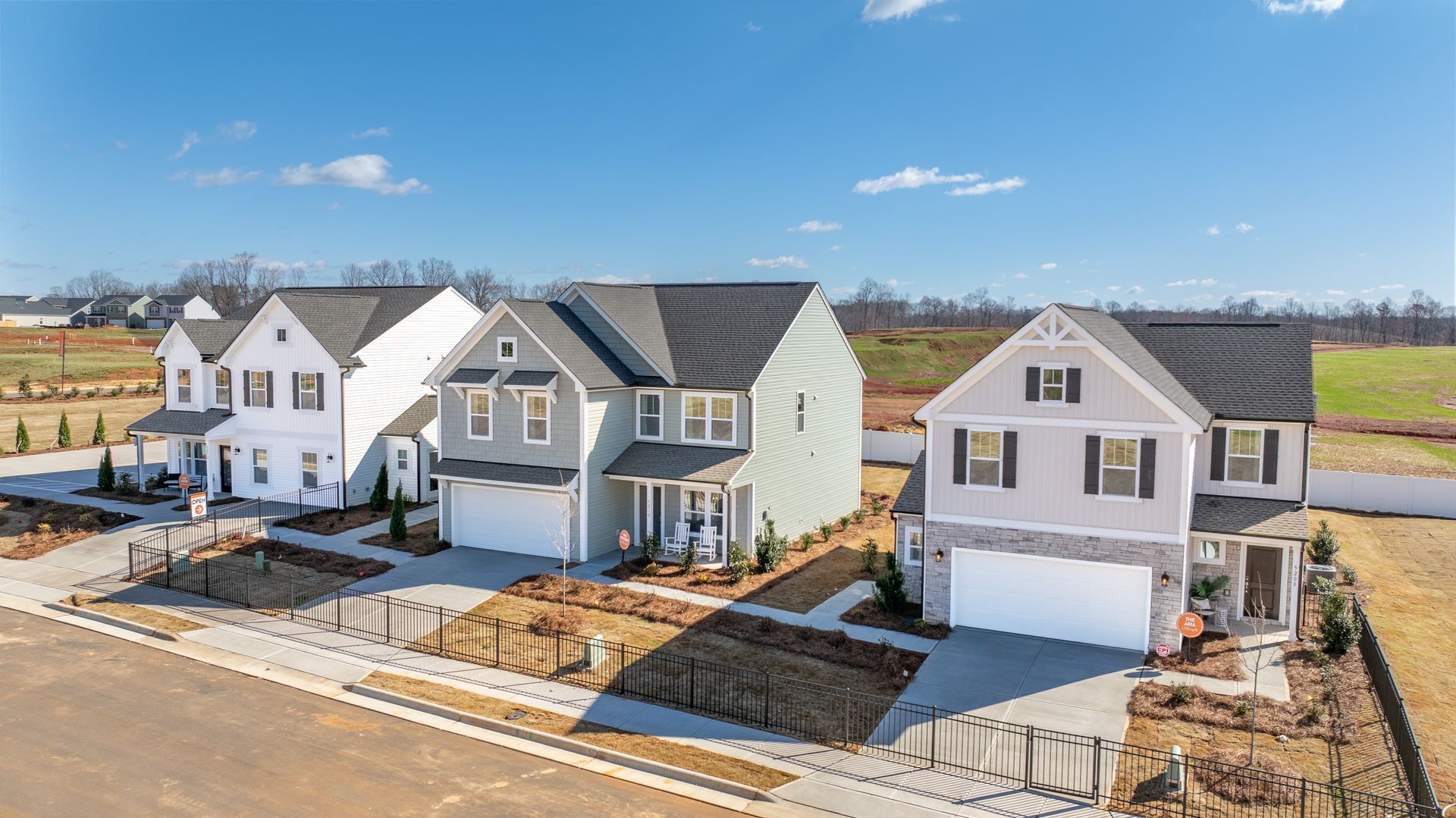 Row of new two-story houses with varying colors and architectural details, under a blue sky.