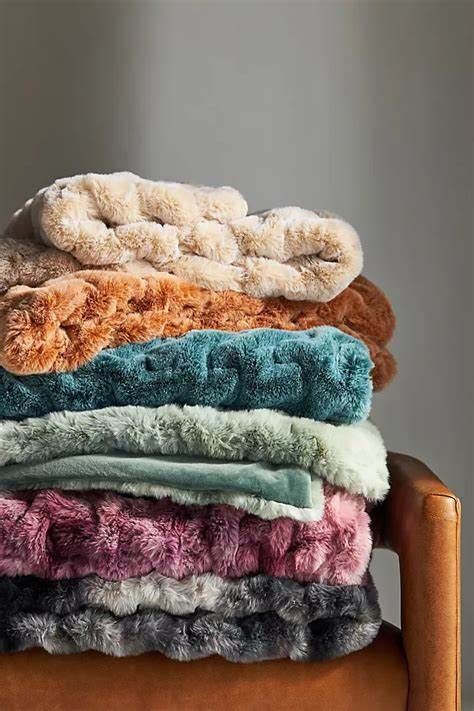 A pile of blankets stacked on top of each other on a chair.