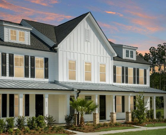 A large white house with a black roof and a large porch.