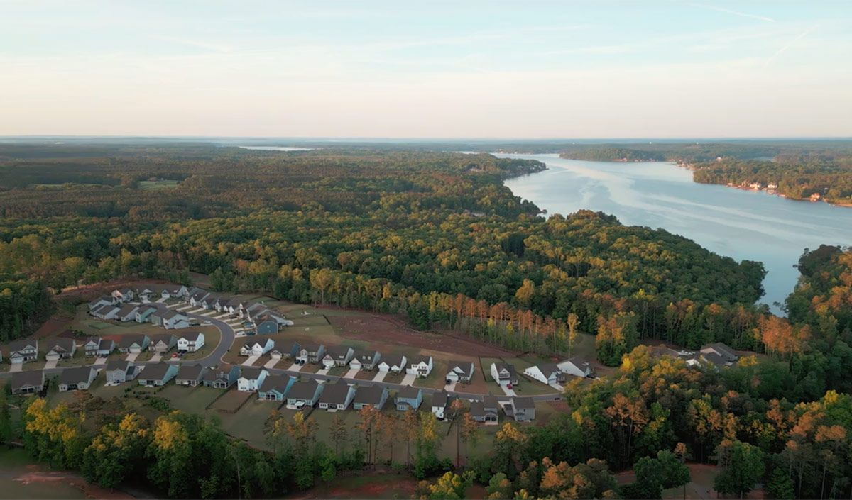 An aerial view of a lake surrounded by trees and houses.