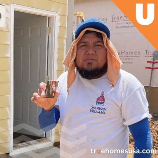 Construction worker holding a Sherwin Williams card, wearing a hat and white shirt.