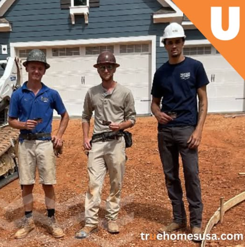 Three construction workers pose in front of a new home.