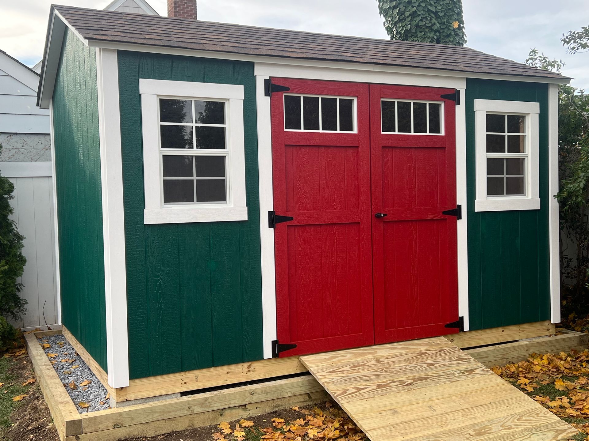 custom shed, green color and red double doors with two white windows