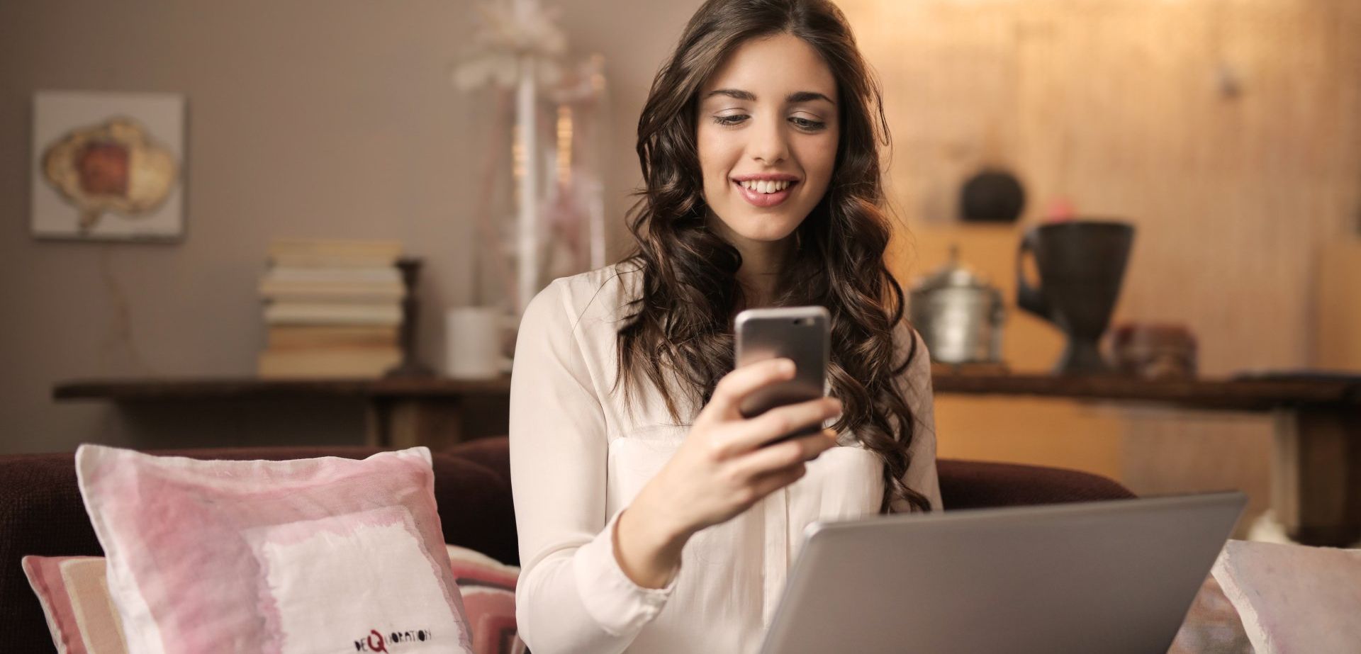 The Rise of tech-savy residents. Women holding smart phone in front of a computer - Empower HOA Web and Software Solutions