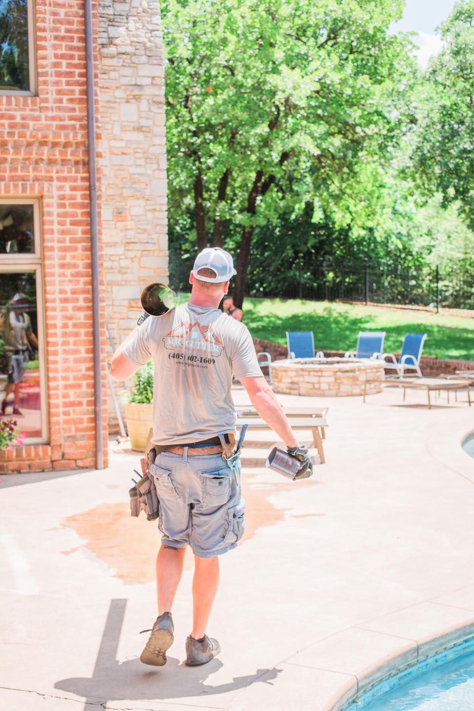 A man is standing on a patio next to a pool.
