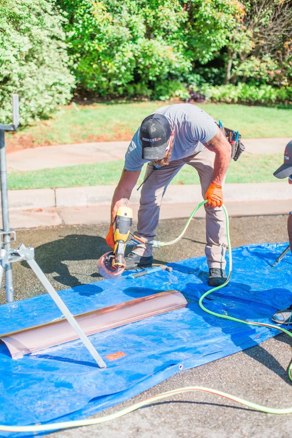 A man is using a drill on a blue tarp.