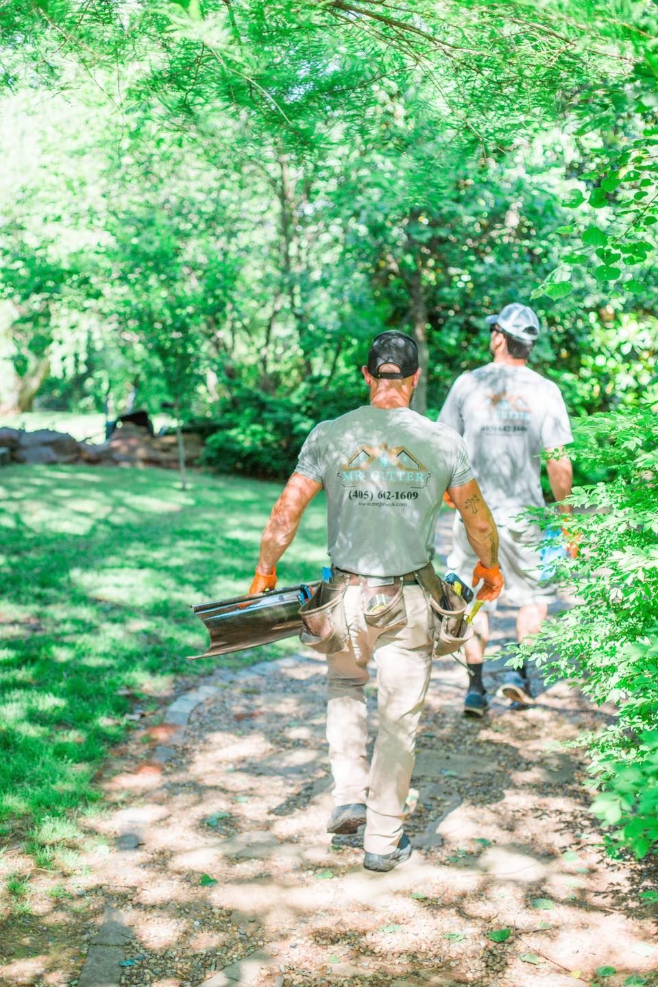 Two men are walking down a path in the woods.