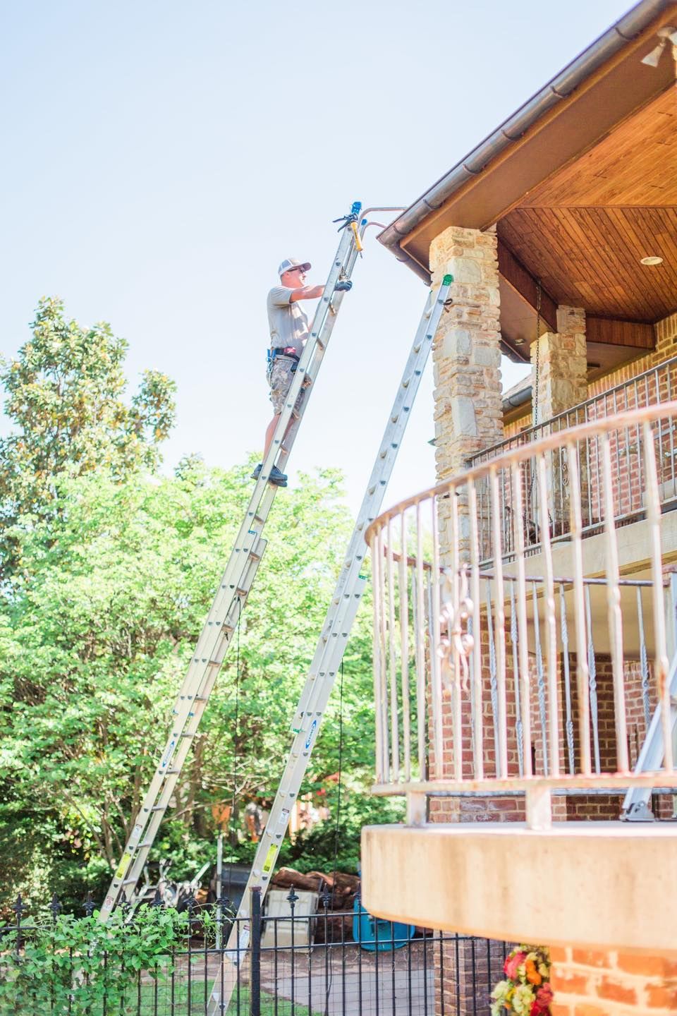 A man is standing on a ladder on the side of a house.