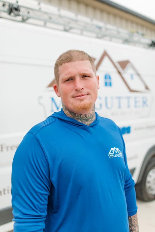 A man in a blue shirt is standing in front of a white van.