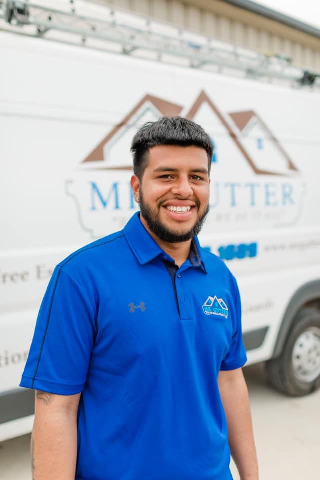 A man in a blue shirt is standing in front of a white van.