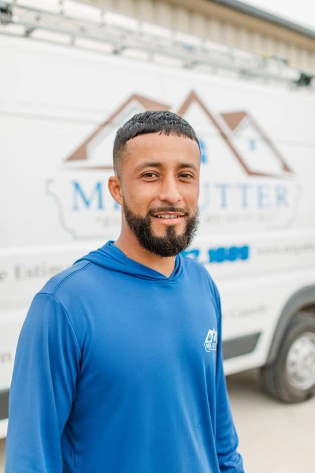 A man with a beard is standing in front of a white van.