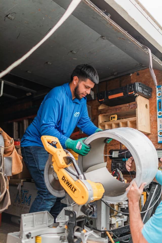 A man is cutting a pipe with a miter saw.