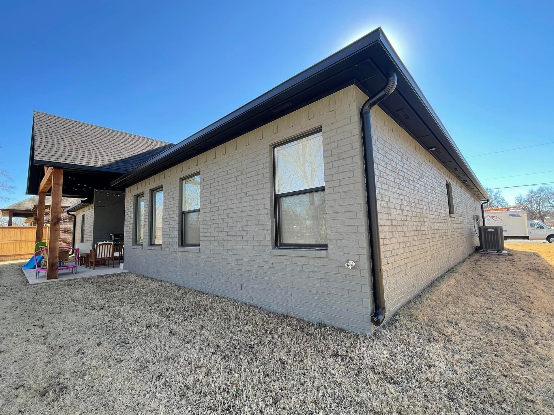 A brick house with a black gutter and a lot of windows