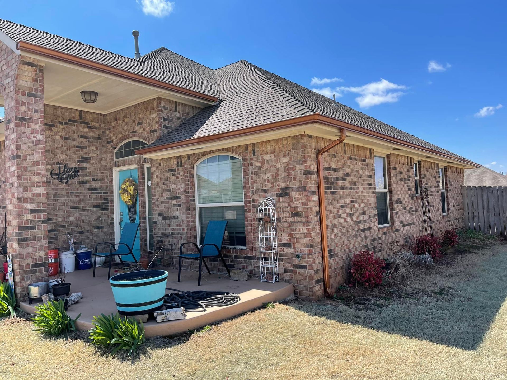 A brick house with a copper gutter and a patio in front of it.