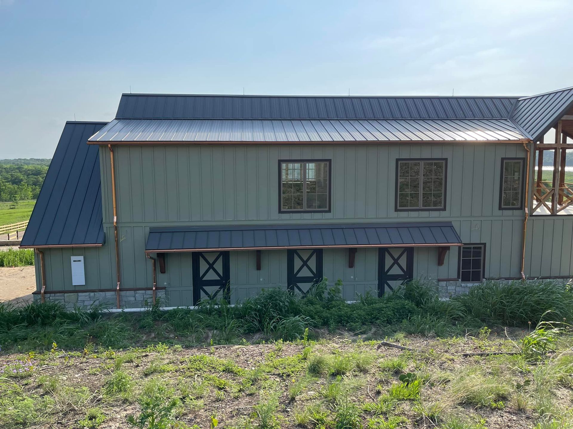 A large house with a black roof is sitting in the middle of a field.