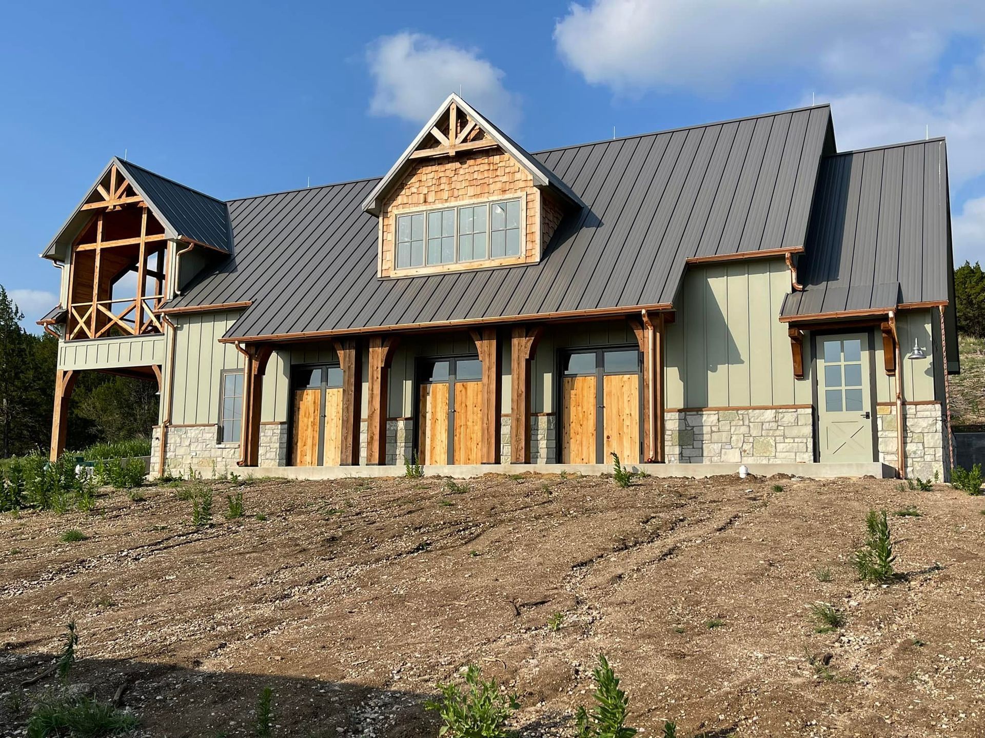 A large house with a metal roof is sitting on top of a dirt hill.