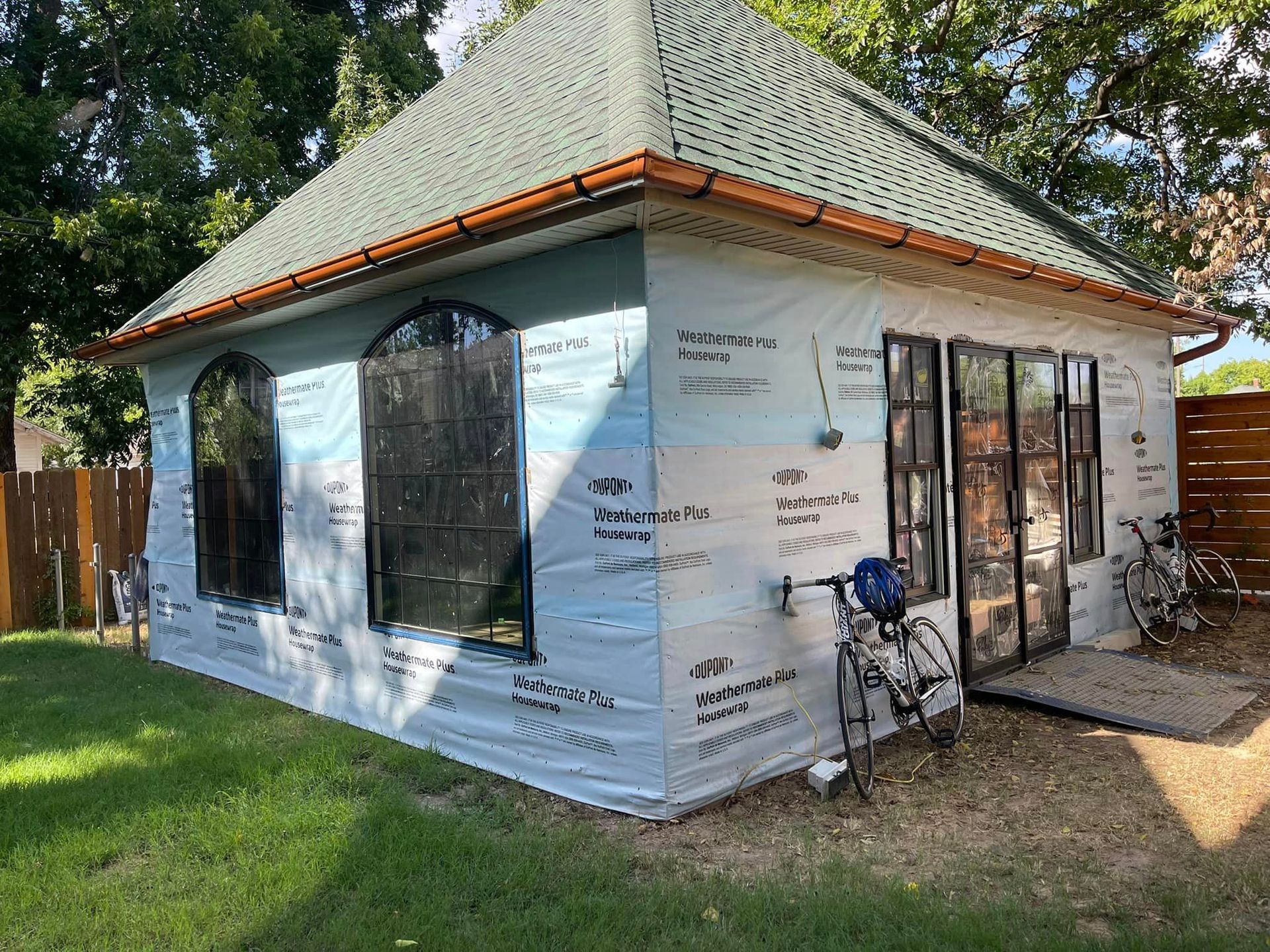 A small house is being remodeled with a bicycle parked in front of it.