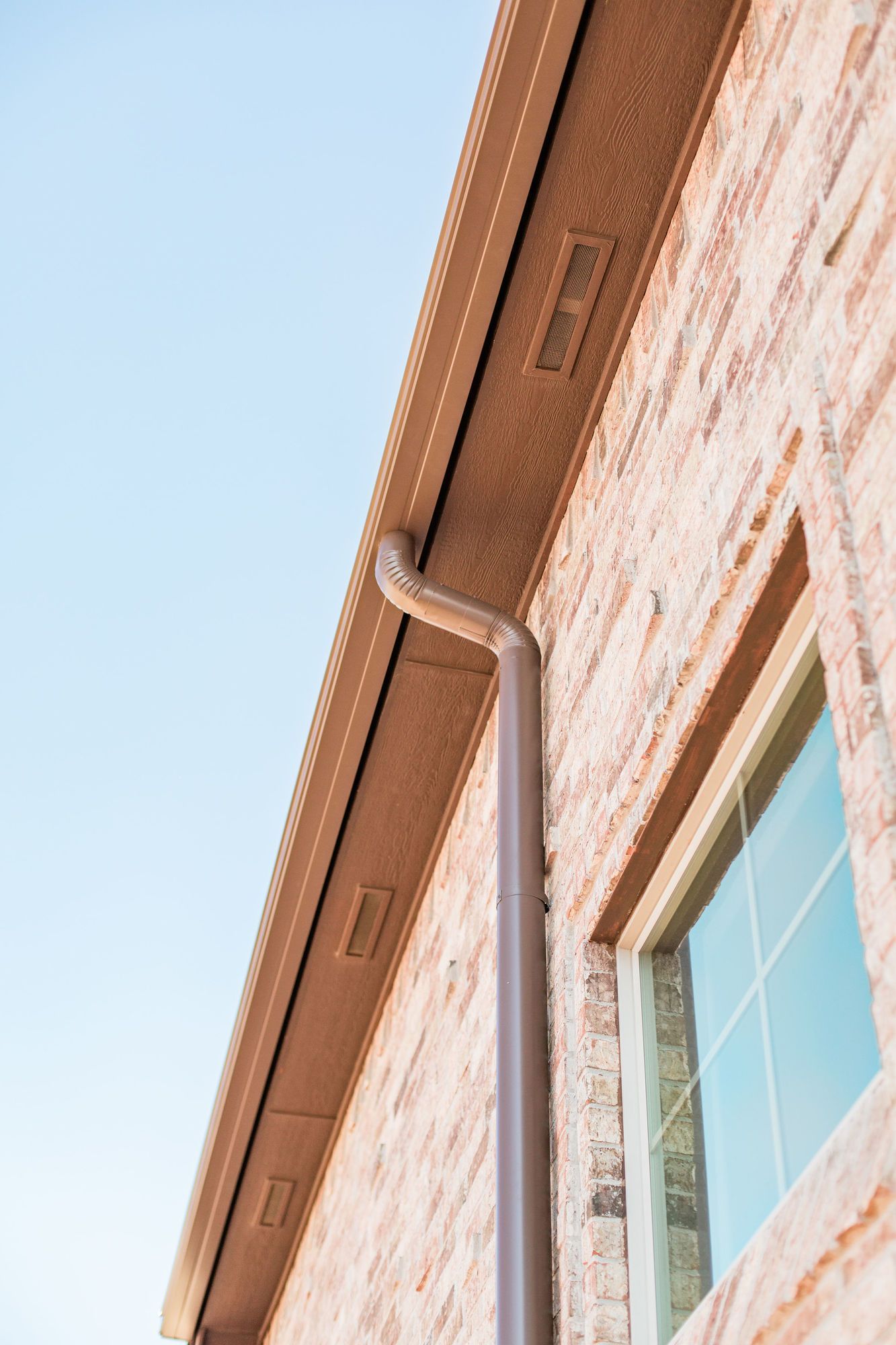 A brick building with a window and a gutter on the side.