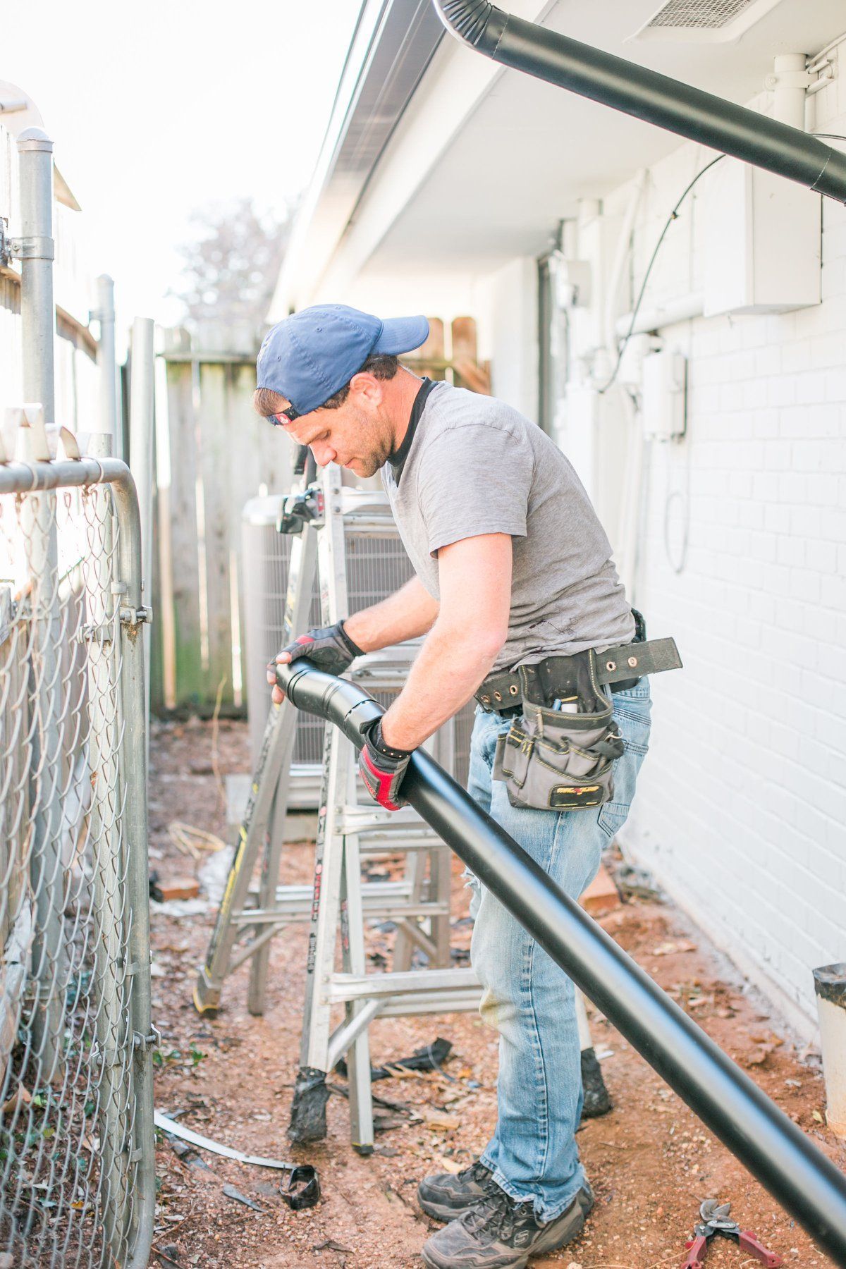 A man is working on a fence with a ladder.
