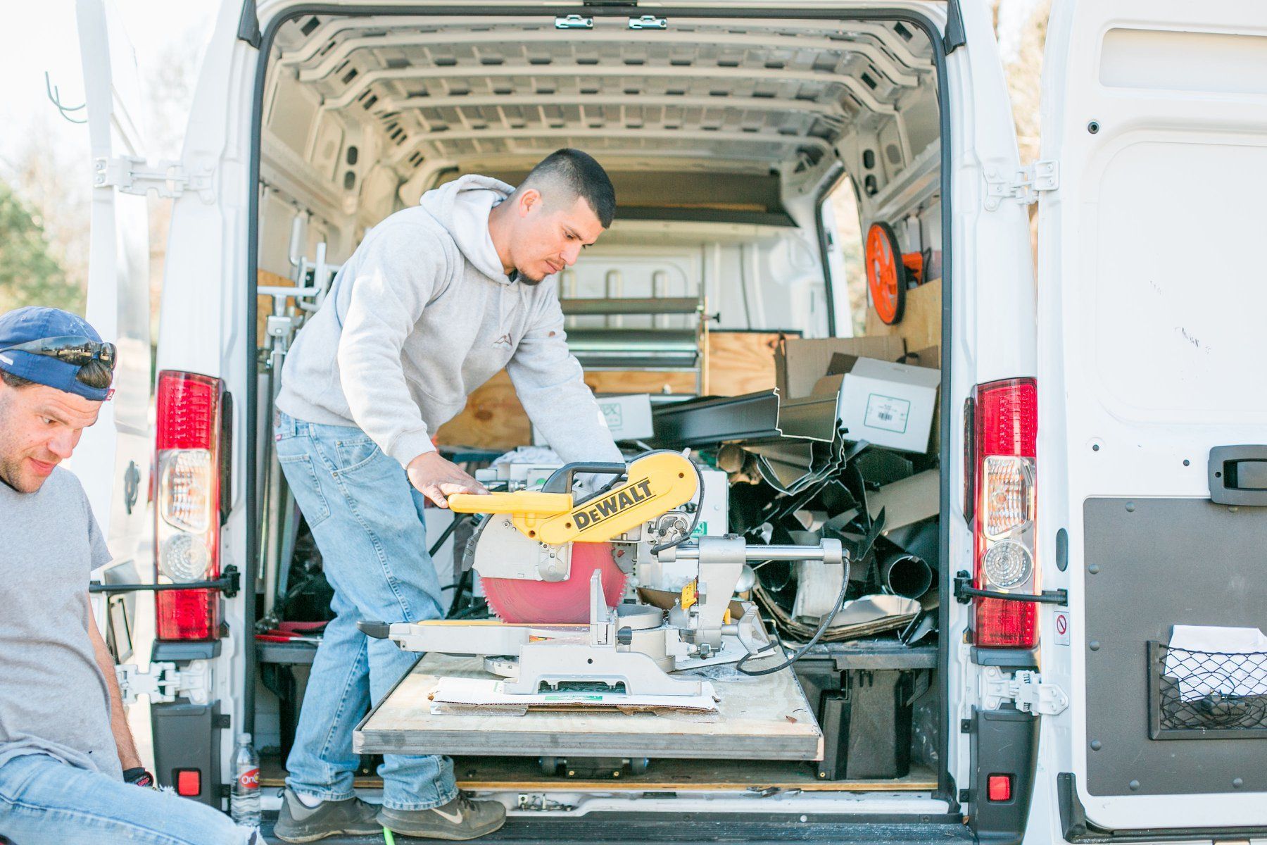 Two men are working in the back of a van.