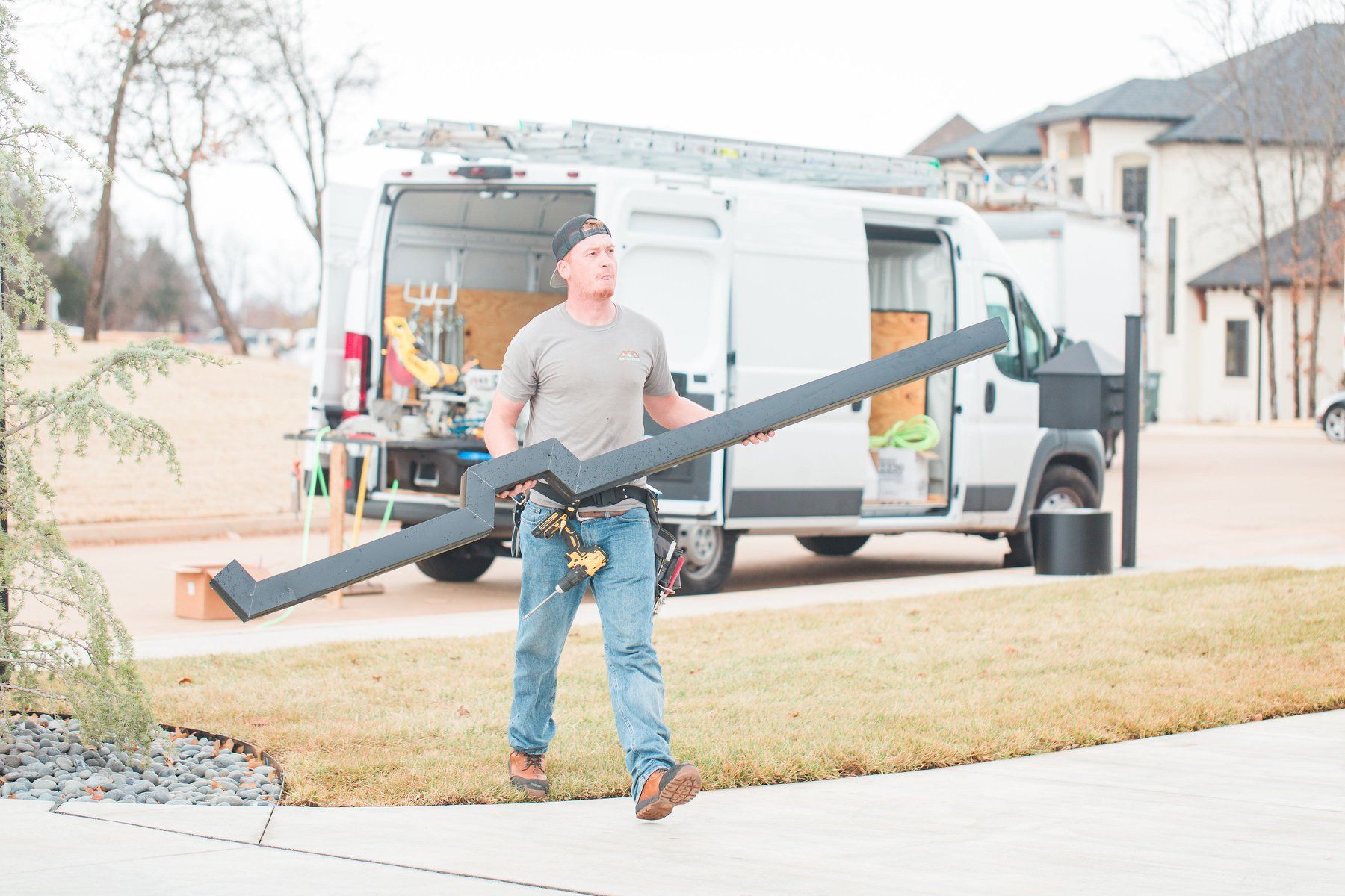 A man is carrying a large piece of metal in front of a van.